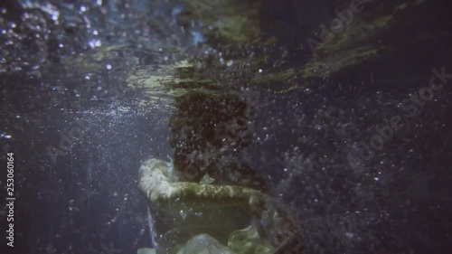 Girl in a white dress with ribbons under the water