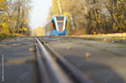 Tram at the city street at the sunny autumn day. Defocused image.