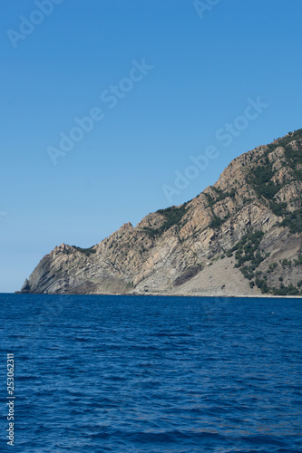 Italy, Cinque Terre, Monterosso, Monterosso al Mare, SCENIC VIEW OF SEA AND MOUNTAIN AGAINST CLEAR BLUE SKY © SkandaRamana