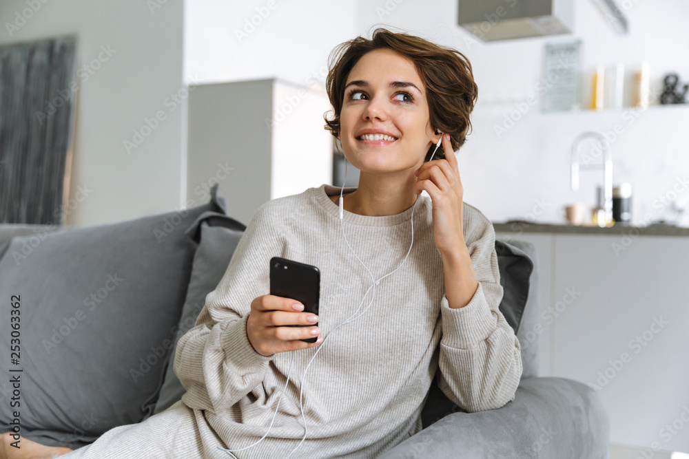 Happy young woman sitting on a couch at home Happy young woman sitting on a couch at home
