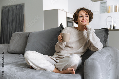 Happy young woman sitting on a couch at home photo