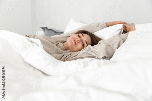 Smiling young girl relaxing in bed in the morning