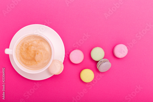 Cup of coffee and colorful macaron on pink background top view. Cozy breakfast. Fashion flat lay. Sweet macaroons.