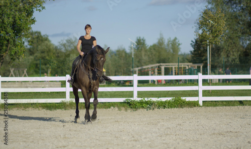 Caucasian girl riding her beautiful mare around the empty outdoor paddock.