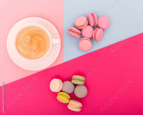 Cup of coffee with macaron on color background from above, flat lay