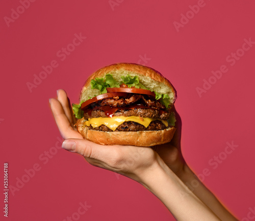Woman hands hold big double cheeseburger burger sandwich with beef tomatoes and cheese photo