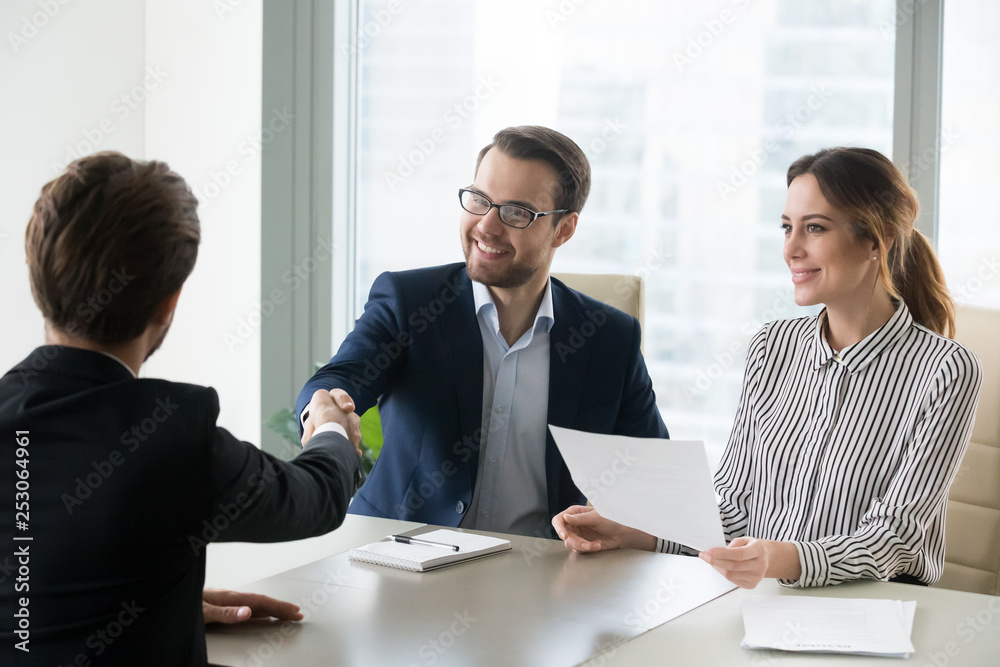 Happy hr manager handshaking hiring successful male job candidate Happy hr manager handshaking hiring successful male job candidate