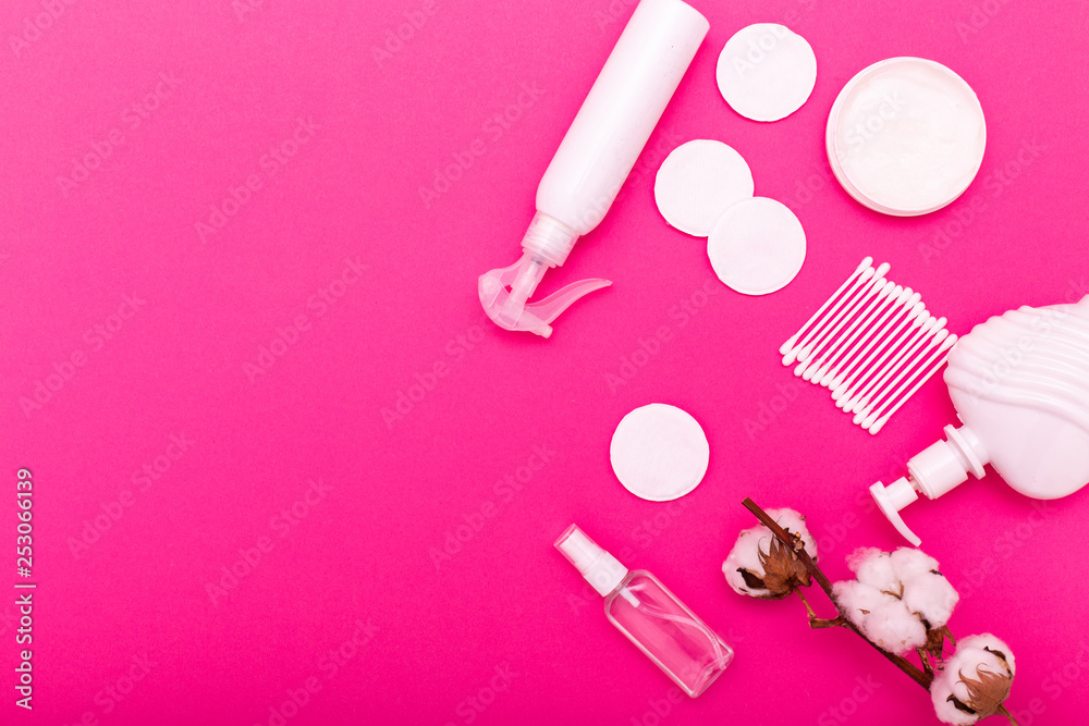 Plastic bottle with lotion, cotton swabs and cotton pads on a pink background