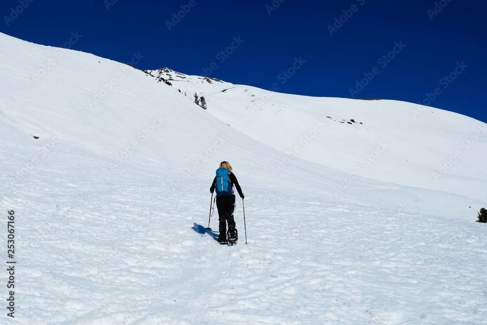 A woman is snowshoeing uphill in the italian alps /Vinschgau/ Tirol