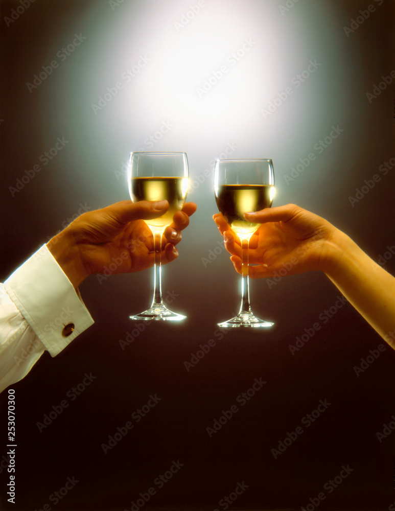a man and a woman, toast with white wine over dark background a man and a woman, toast with white wine over dark background