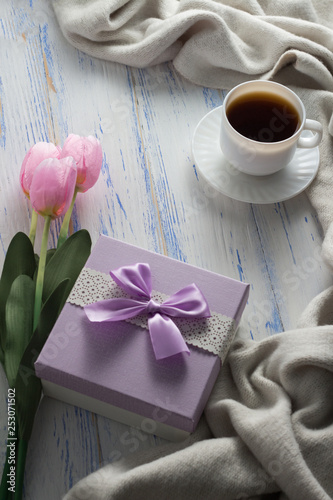 Fototapeta Naklejka Na Ścianę i Meble -  Cup with Coffee, Scarf, Gift, Tulips on the White Wooden Table. Concept of Spring