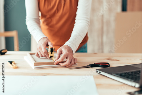 Photos Female carpenter tape measuring picture frame in workshop
