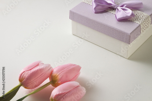 Three Pink Tulips and a Gift Box On The White Background. Artificial flowers. Copy space