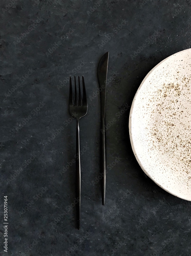empty white plate with knife and fork on dark background empty white plate with knife and fork on dark background