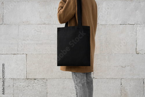 woman holding black tote bag on the wall background