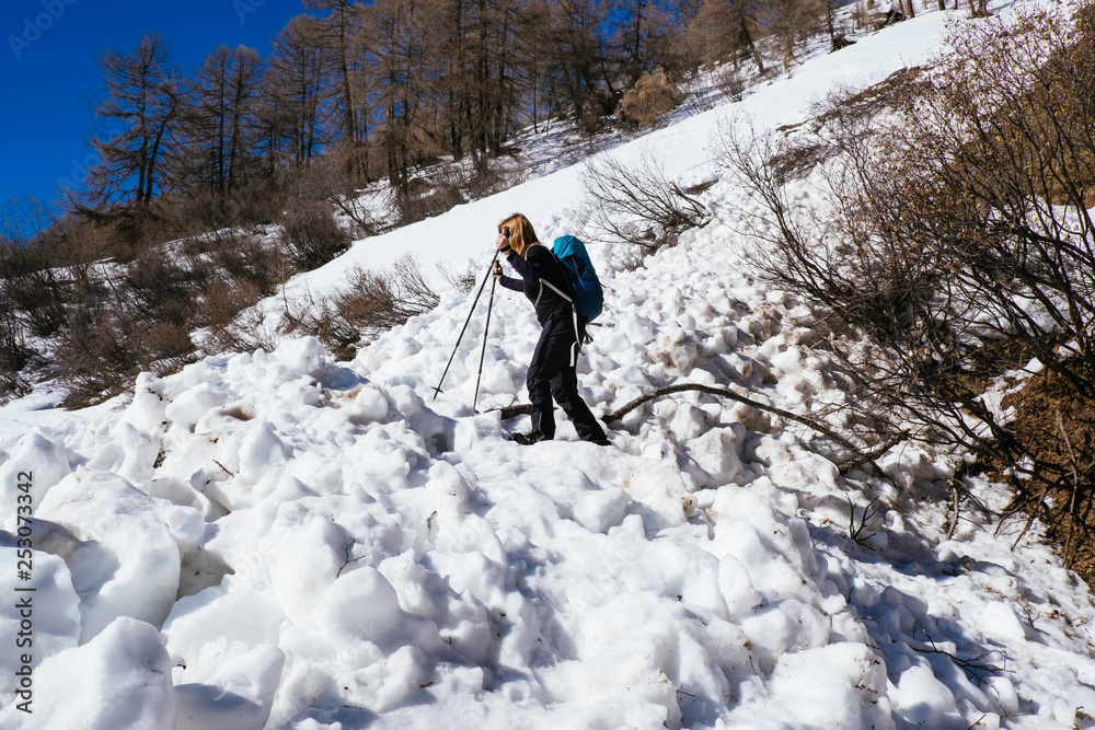 A woman mithe snowshoe is crossing a wet snow avalanche in the italian alps