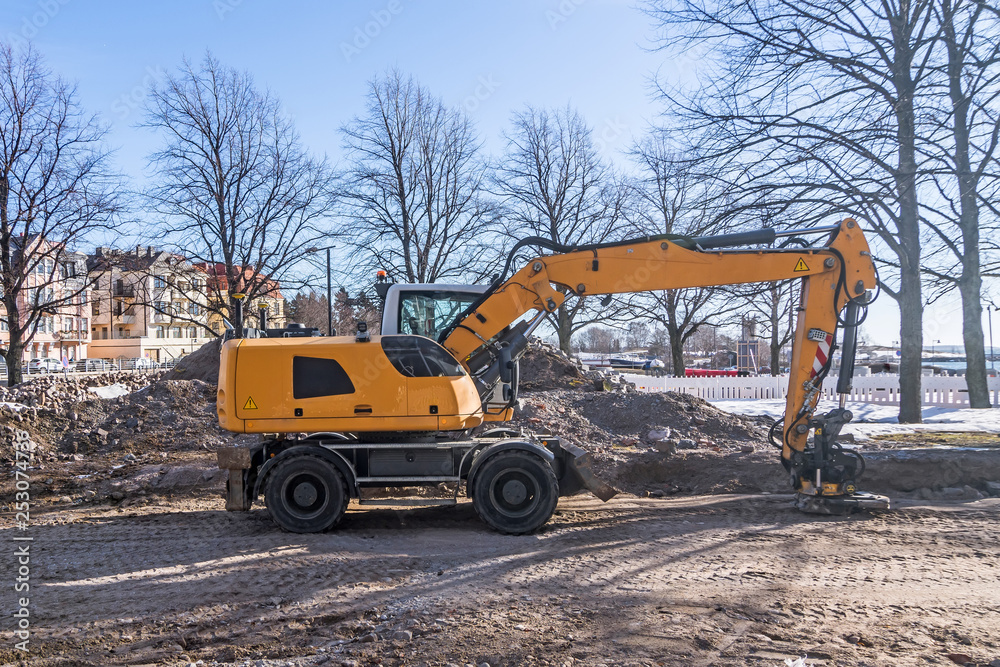Excavator on a city street, reconstruction of communication along roads and pavements Excavator on a city street, reconstruction of communication along roads and pavements