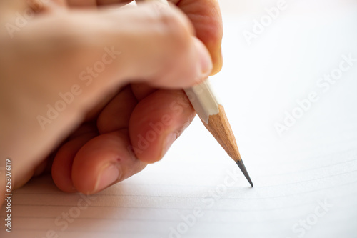 Hand writing letter on white paper background, A white pencil, Close up & Macro shot, Selective focus, Stationery concept