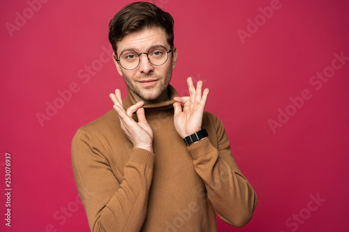 Cheerful man laughing and looking at camera. Portrait of a happy young man standing over pink background photo