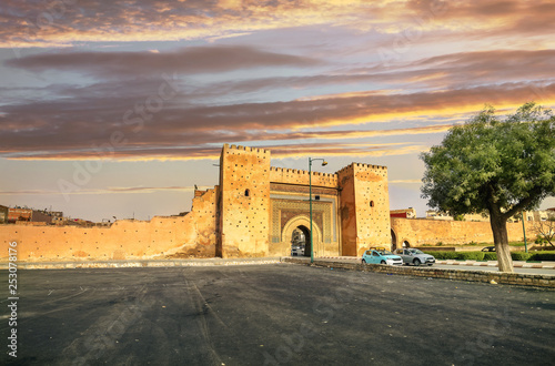 Town wall and gate Bab el-Khamis in medina of Meknes at sunset. Morocco