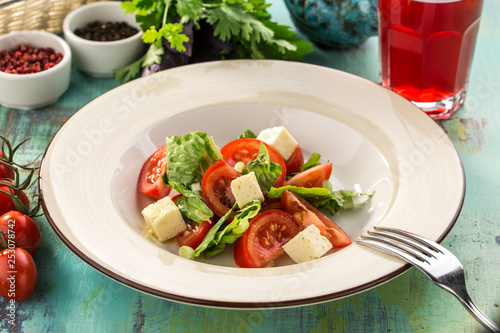 tomato salad with marinated cheese and herbs on blue wooden table