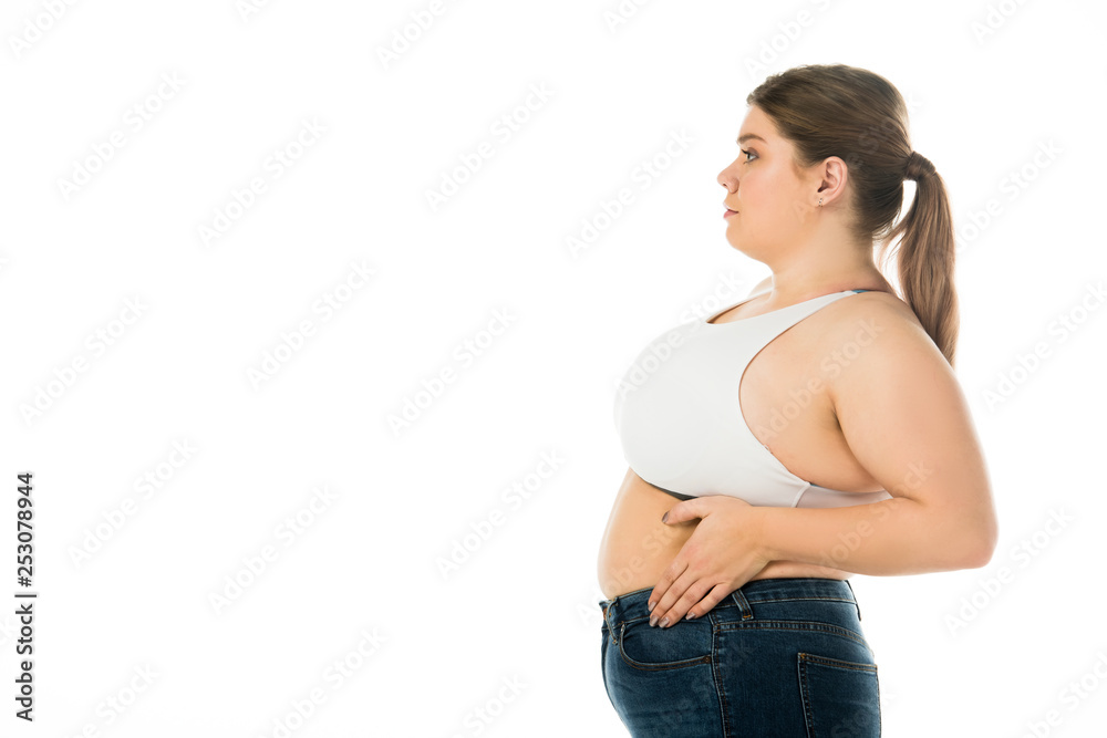 side view of overweight woman in denim posing with hand on belly isolated on white side view of overweight woman in denim posing with hand on belly isolated on white