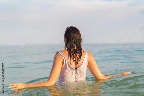 A woman in a shirt goes into the water.Woman in sea water