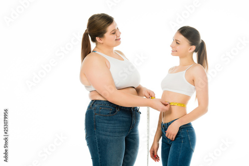 happy overweight woman measuring waist of slim woman isolated on white