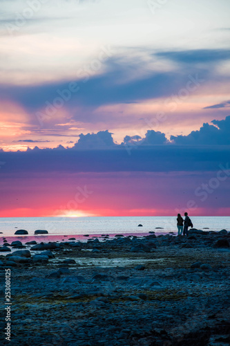 Couple at the seaside during colorful sunset.