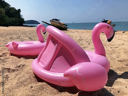 Water activities equipment on the beach: inflatable toys pink flamingo on the foreground and Jet Skis - personal watercraft (PWC) in a distance on a background. Image of holiday and tropical resort.  photo