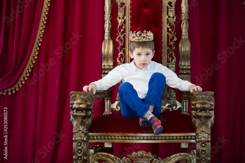 Little boy in a crown in a luxurious chair