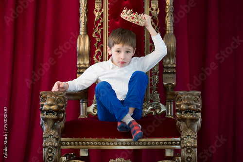 Little boy in a crown in a luxurious chair.Dress up the crown