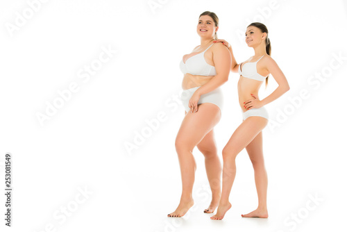 happy slim and overweight women in underwear posing together isolated on white, body positivity concept