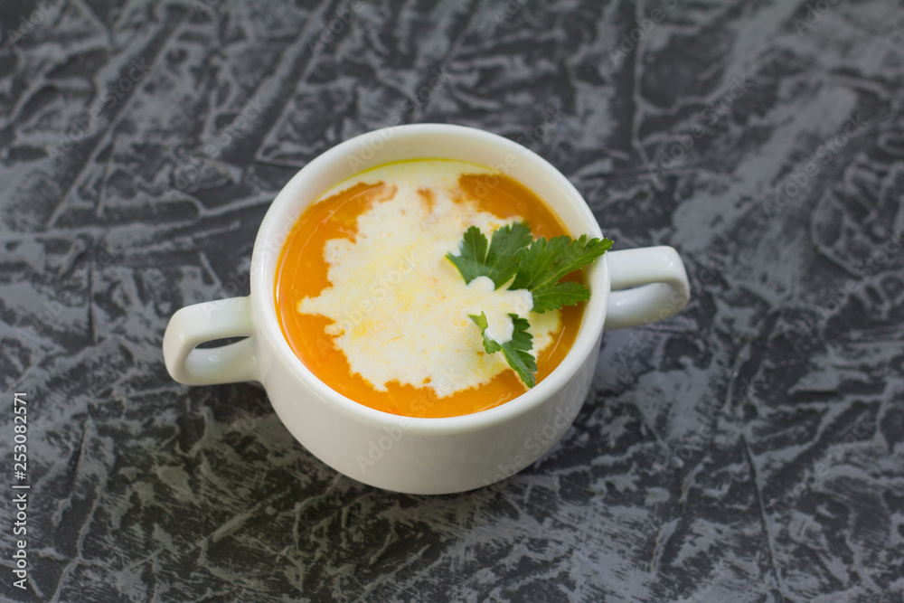 pumpkin soup puree with cream and parsley on grey background pumpkin soup puree with cream and parsley on grey background