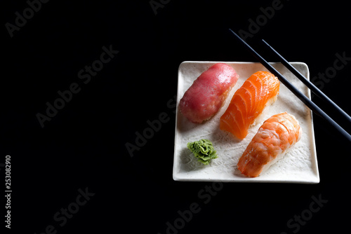 Macro shot of sashimi, uramaki and nighiri, Japanese dish consisting of rice, salmon or tuna, shrimp in black . Concept of Japanese restaurant