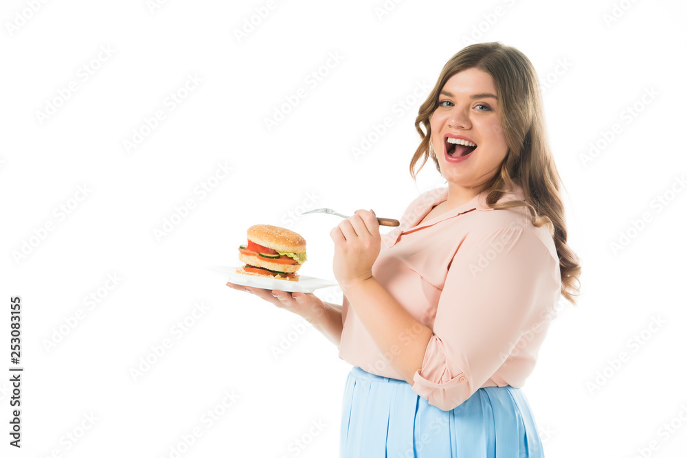 happy smiling woman with open mouth holding tasty burger on plate and fork isolated on white happy smiling woman with open mouth holding tasty burger on plate and fork isolated on white