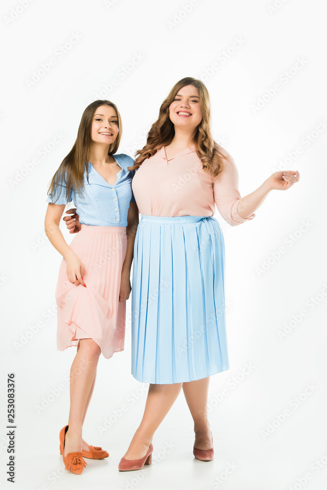 smiling elegant overweight and slim women embracing on white background smiling elegant overweight and slim women embracing on white background