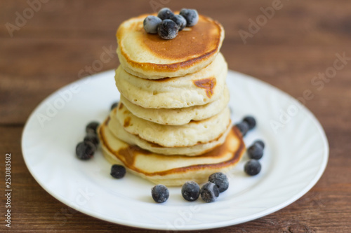 stack of pancakes with black currant berries on wooden background