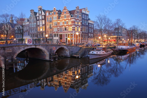 Reflection of crooked and colorful heritage buildings along Brouwersgracht Canal and with Lekkeresluis Bridge on the left, Amsterdam, Netherlands.