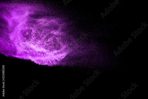 purple dust particles explosion on black background. Color powder dust splashing.