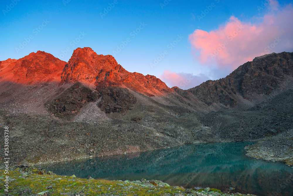 Kyshkager stony mountain slopes with mountain lake at sunset with bright clouds in Teberdinsky Reserve