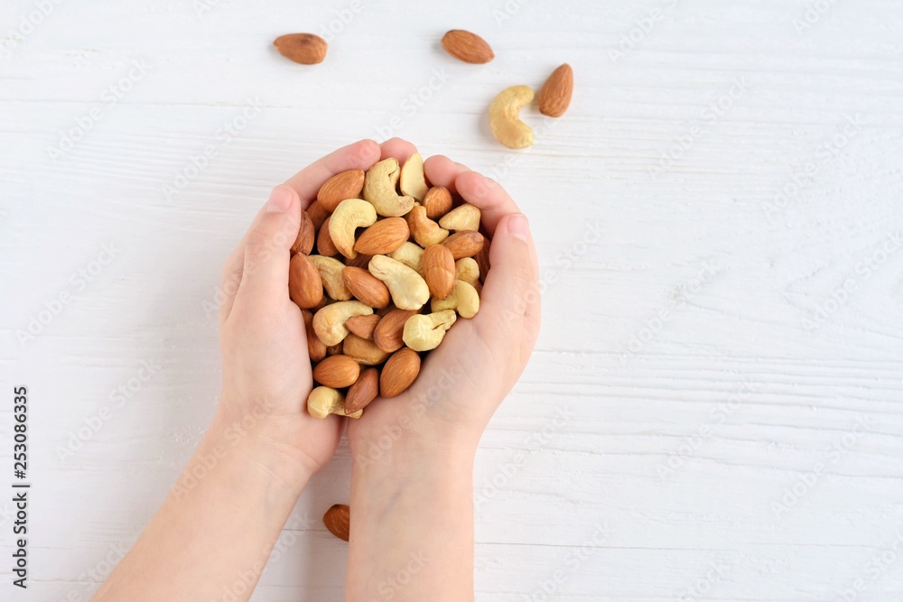 White children hands holding heap of nuts mix with selective focus on blurred background. Almond and cashew nuts in the hands of a child. Roasted almond and cashew nuts. Delicious protein snack White children hands holding heap of nuts mix with selective focus on blurred background. Almond and cashew nuts in the hands of a child. Roasted almond and cashew nuts. Delicious protein snack