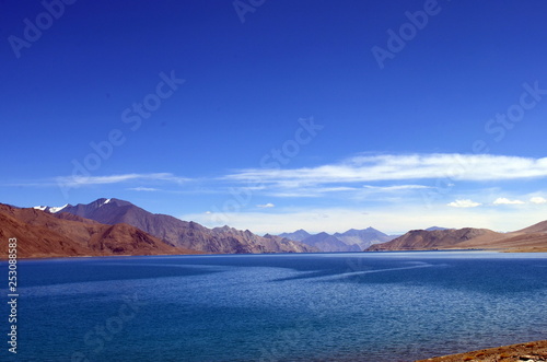 View of Pangong Lake (Tso) from the beachside. The clear blue water stands out amidst skies and Himalayan range. On the border of India and China, this is one of the most recognized lake worldwide © PhotographrIncognito