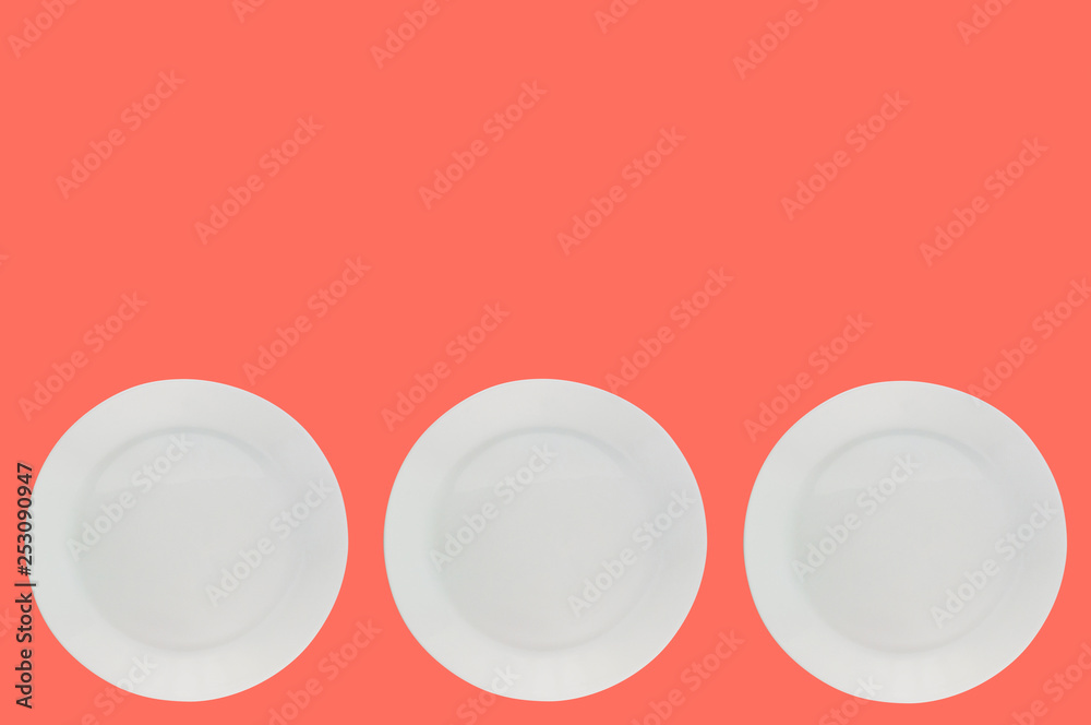 Set of ceramic circle fragile plates on background of living coral color with copy space for your text. Top view Set of ceramic circle fragile plates on background of living coral color with copy space for your text. Top view