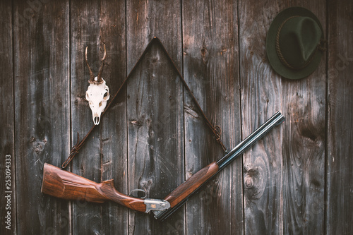 Professional hunters equipment for hunting. Rifle, Deer, Roe deer trophy sculs and others on a wooden black background. Trophy sculs from Roe deer and Deer on the wall.