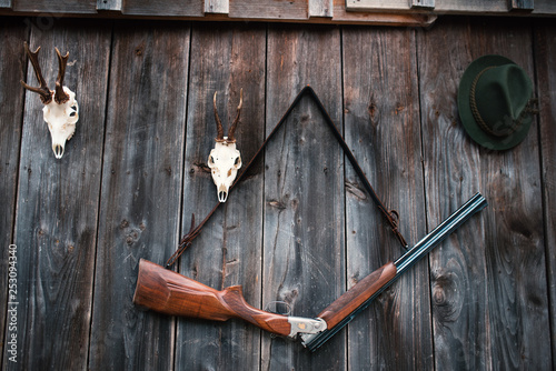 Professional hunters equipment for hunting. Rifle, Deer, Roe deer trophy sculs and others on a wooden black background. Trophy sculs from Roe deer and Deer on the wall.
