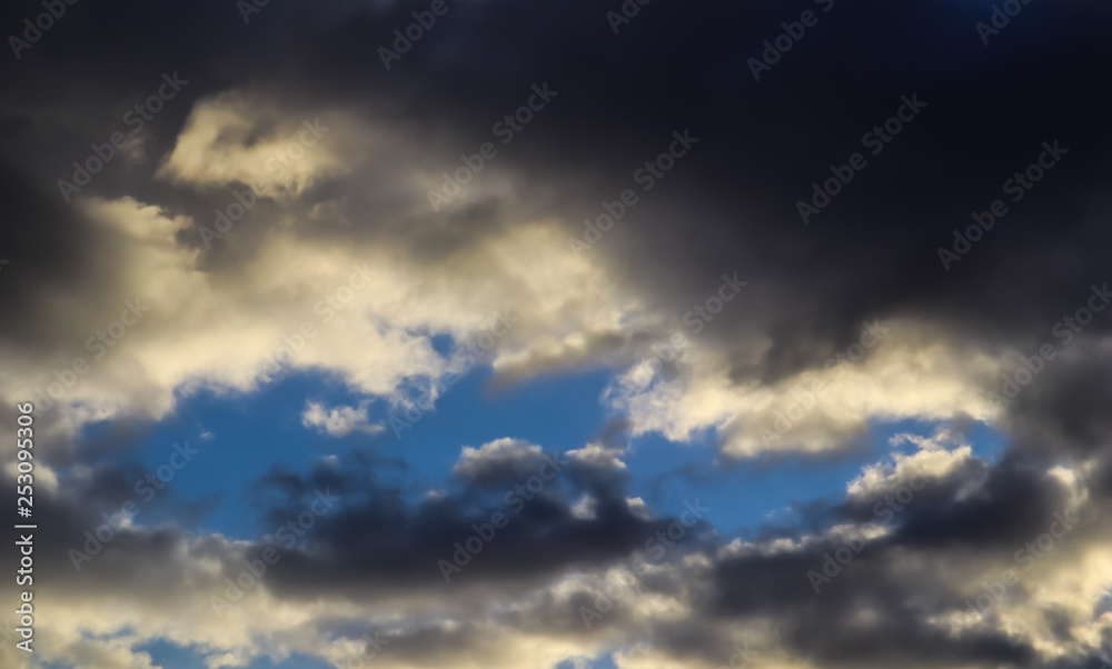 Blue sky and dark clouds with sunlight