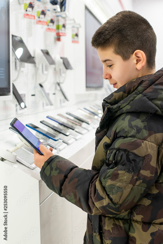 Smartphones on shelf in the store. Boy buying mobile phone in technology shop. Smartphones on shelf in the store. Boy buying mobile phone in technology shop.