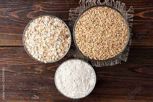 Rolled oats, oat and flour on dark wooden background.
