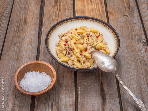 Seashell pasta with turkey minced meat in a deep ceramic plate on the board table photo